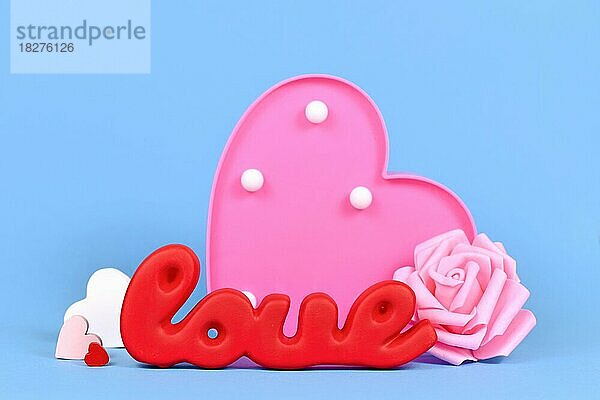 Valentinstag Dekoration mit roten Wort Liebe  Rosen und Herz Ornamente auf blauem Hintergrund