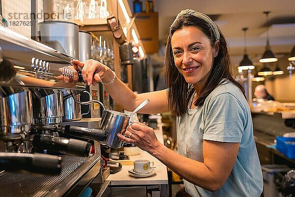 Kaffeehausbesitzerin  die Kaffee in einer Kaffeemaschine zubereitet und einen Milchkaffee zubereitet