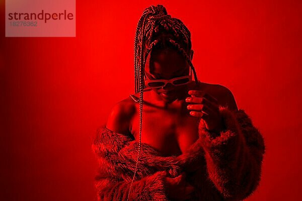 Attraktive schwarze ethnische Frau mit Zöpfen mit roten Lichtern  Trap-Tänzerin mit Sonnenbrille