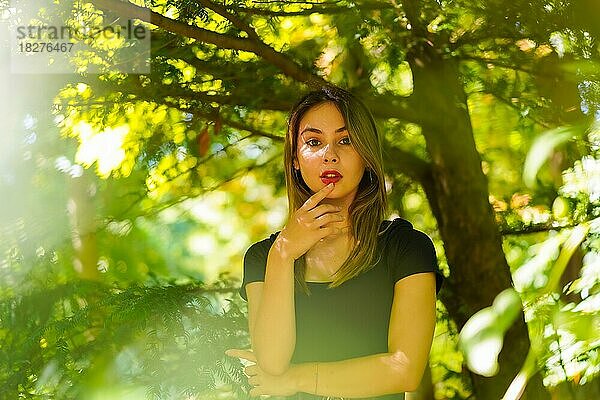 Eine junge brünette Frau in der Natur im Naturpark  im Schatten eines Baumes