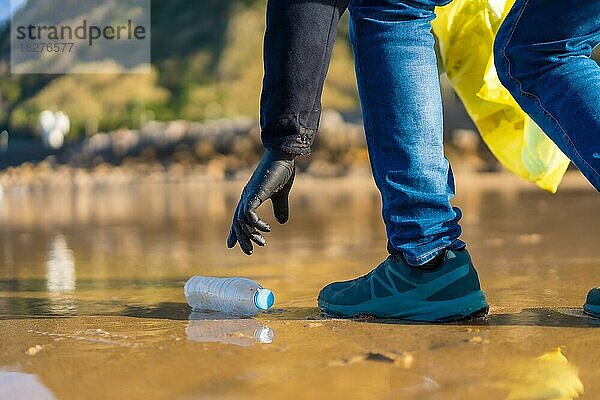 Meeresverschmutzung  nicht erkennbare Person  die am Strand spazieren geht und Plastik sammelt. ökologisches Konzept