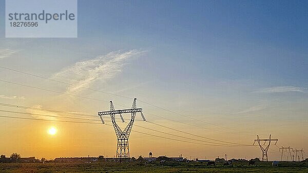 Hochspannungsmasten  ländliche Landschaft mit Strommasten in einer Reihe  bei Sonnenuntergang