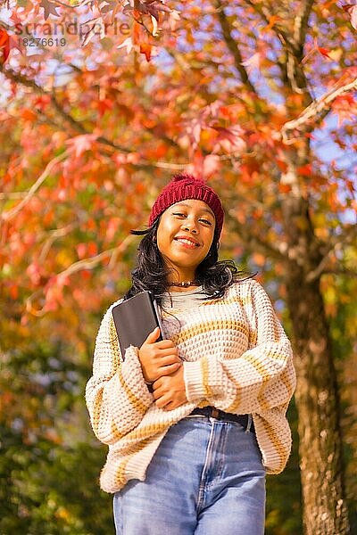 Porträt eines asiatischen Mädchens im Herbst mit einer Tablette lächelnd in einem Wald von roten Blättern  Technologie-Konzept