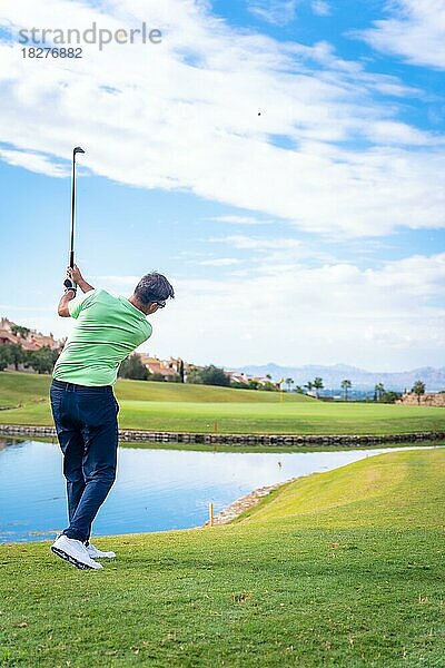 Mann spielt Golf in einem Golfclub an einem See  schlägt den Ball