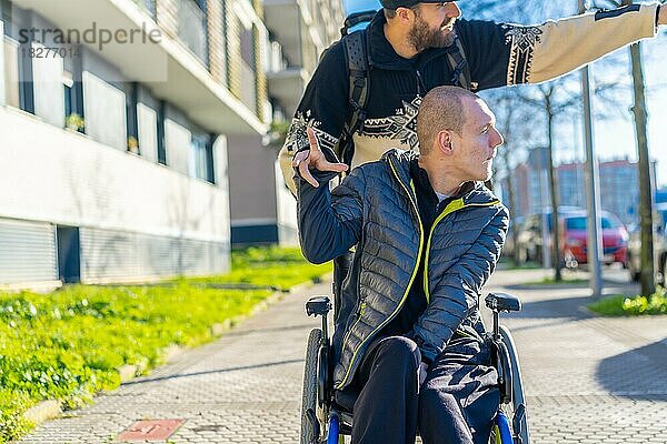 Behinderte Person im Rollstuhl lacht mit einem Freund im Rollstuhl auf der Straße im Winter