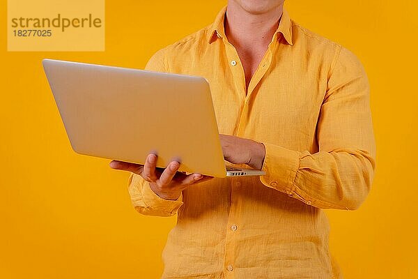 Kaukasischer blonder Geschäftsmann auf einem gelben Hintergrund  Porträt mit einem Laptop