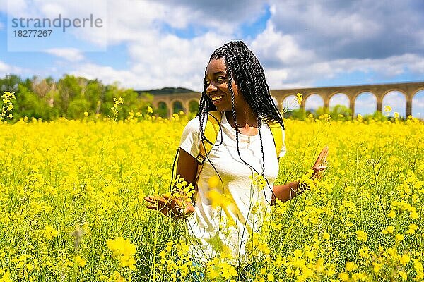 Eine Reisende schwarz ethnischen Mädchen mit Zöpfen in einem Feld von gelben Blumen