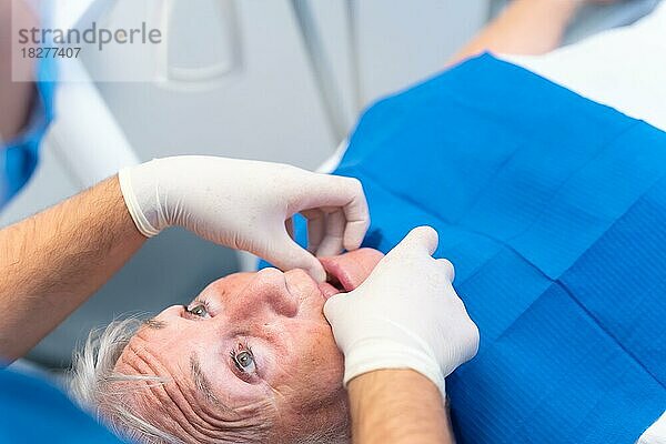Zahnklinik  Detail der Hände eines Arztes  der die Zähne einer älteren Frau kontrolliert