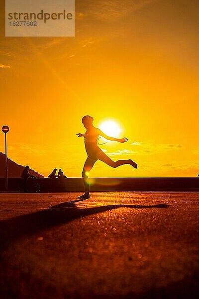 Silhouette einer jungen Tänzerin bei einem Sprung am Strand bei Sonnenuntergang