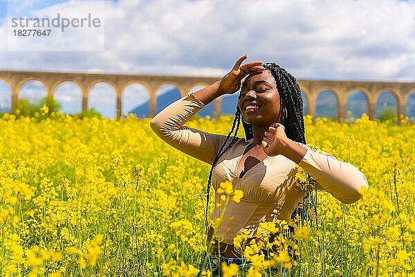 Lebensstil  Porträt eines schwarzen ethnischen Mädchens mit Zöpfen  in einem Feld mit gelben Blumen