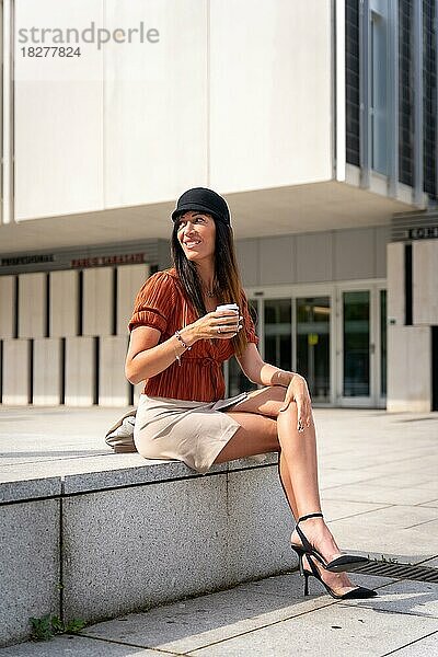 Porträt einer Geschäftsfrau vor dem Büro mit einem Kaffee in der Hand  Blick nach links