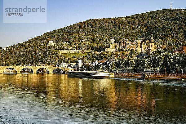 Blick auf Heidelberg  das Schloss  die Alte Brücke (Karl-Theodor-Brücke)  das Stadttor und den Fluss Neckar im Herbst zur goldenen Stunde  ein Schiff fährt auf dem Neckar  Langzeitbelichtung  Rhein-Neckar-Kreis  Baden-Württemberg  Deutschland  Europa