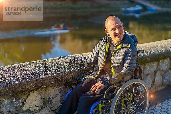 Eine behinderte Person im Rollstuhl in einem Park bei Sonnenuntergang lächelnd