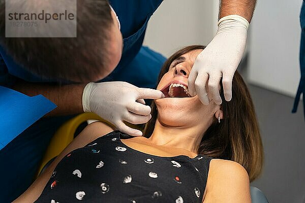 Zahnklinik  Zahnarzt schaut sich die Prothese eines jungen Patienten an