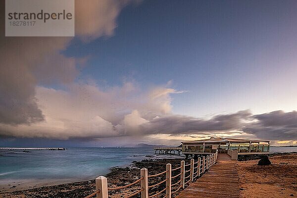 Langzeitbelichtung zum Sonnenaufgang an der Küste bei Corralejo  schöne bucht mit Steg am Morgen  Parque Natural de Corralejo  Fuerteventura  Kanarische Inseln  Spanien  Europa