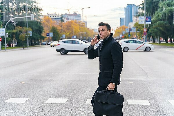 Kaukasischer Geschäftsmann mittleren Alters telefoniert beim Überqueren der Straße in der Stadt