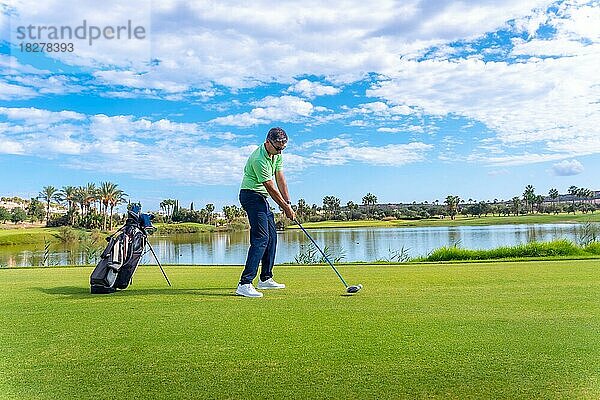 Männlicher Golfspieler auf einem professionellen Golfplatz. Golfer schlägt den Ball mit Driver Stick neben einem See