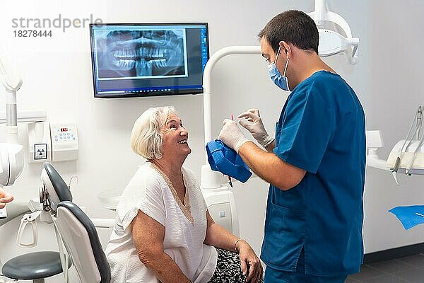 Zahnklinik  Zahnarzt  der sich mit einer älteren Frau amüsiert  die auf dem Tisch liegt
