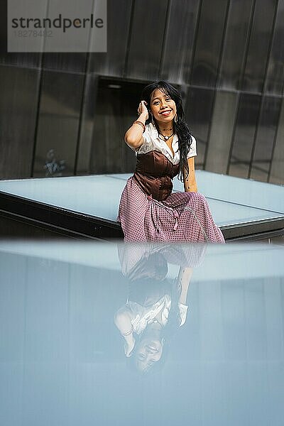 Ein asiatisches Mädchen in einem traditionellen langen Kleid  das auf einem Glas sitzt