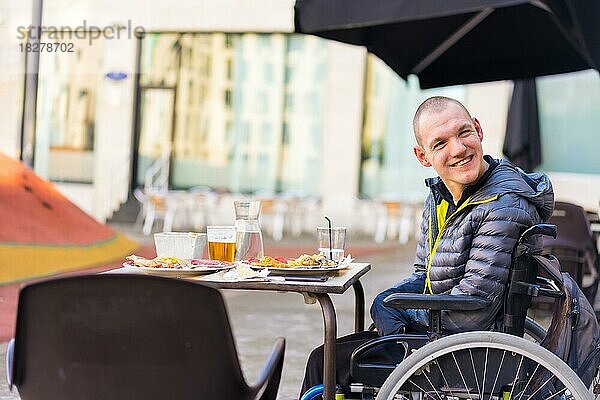 Eine behinderte Person im Rollstuhl in einem Restaurant lächelt und hat Spaß