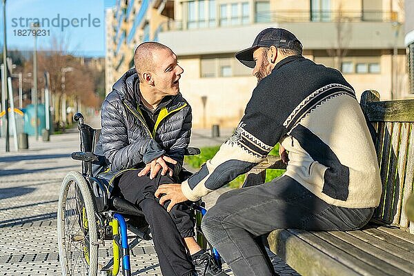 Ein behinderter Mensch im Rollstuhl mit einem Freund  der sich amüsiert  Normalität für Behinderte