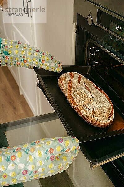 Laib Brot auf dem Backblech mit Ofenhandschuhen