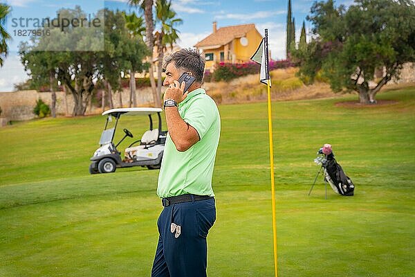 Geschäftsmann  der Golf spielt und einen Arbeitsanruf mit dem Telefon aus dem Club entgegennimmt
