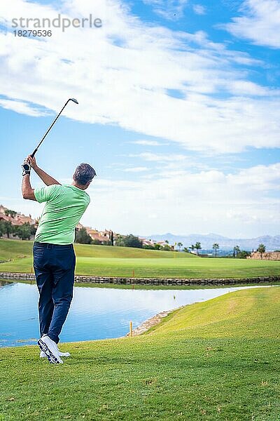 Mann spielt Golf in einem Golfclub an einem See  schlägt den Ball