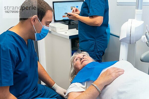 Zahnklinik  Zahnarzt  der einer älteren Frau das Ergebnis der Prothesenuntersuchung erklärt