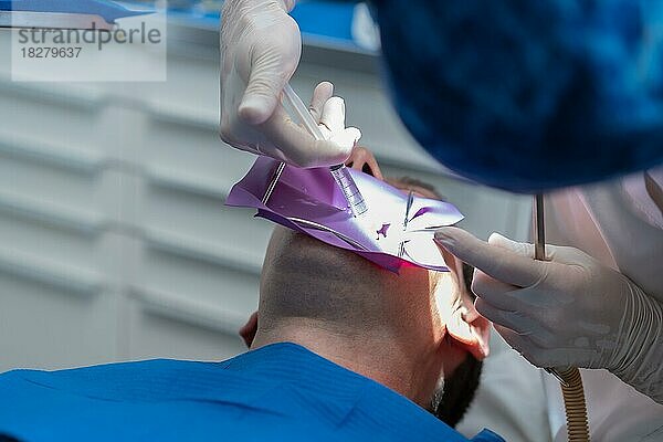 Zahnklinik  Detail eines Arztes  der eine endodontische Behandlung an einem Patienten in voller Aktion durchführt