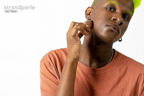 Ein androgyner schwarzer Mann  der posiert und sich schminkt  LGTBI-Konzept  Auftragen von Rouge  weißer Hintergrund