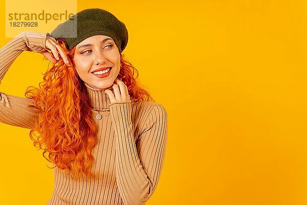 Rothaarige Frau mit Baskenmütze im Studio auf einem gelben Hintergrund  Kopierraum  Porträt hübsches Modell