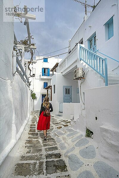 Junge Frau mit rotem Rock in den Gassen der Altstadt Chora  Kykladische weiße Häuser mit blauen Fensterläden  Mykonos Stadt  Mykonos  Kykladen  Griechenland  Europa