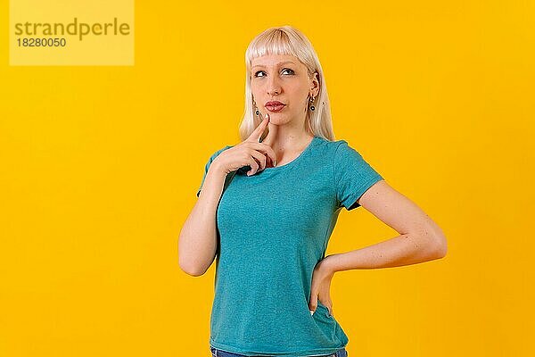 Porträt mit nachdenklicher Pose  blondes kaukasisches Mädchen im Studio auf gelbem Hintergrund