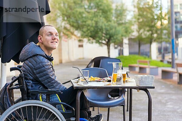 Eine behinderte Person  die auf der Terrasse eines Restaurants isst