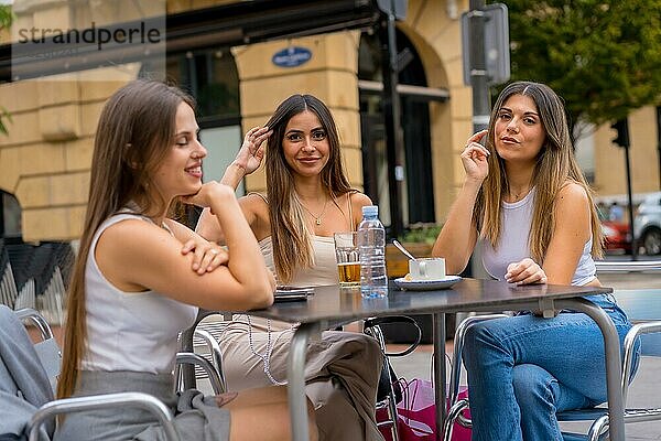 Porträt von jungen Freundinnen  die an einem Nachmittag auf der Terrasse einer Cafeteria etwas trinken