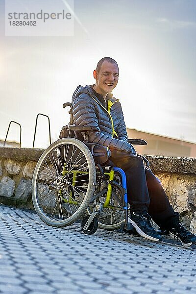 Porträt einer behinderten Person im Rollstuhl  die sich bei Sonnenuntergang in einem Park amüsiert