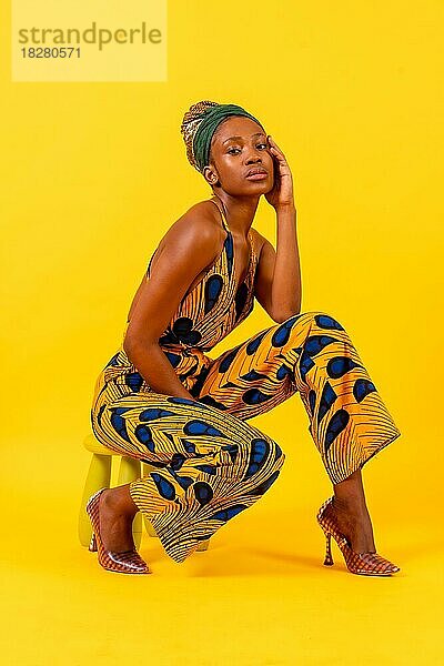 Afrikanische junge Frau in traditionellem Kleid auf gelbem Hintergrund  verführerischer Blick