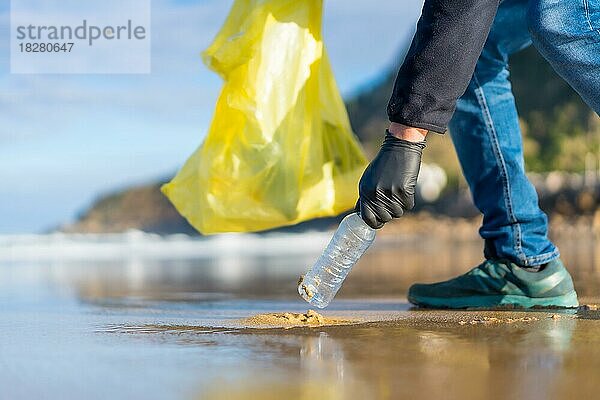 Unbekannte Person  die am Strand Müll oder Plastik sammelt. Ökologiekonzept