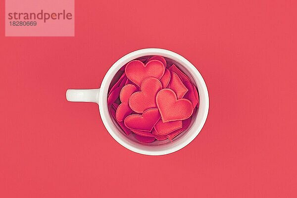 Draufsicht auf eine mit roten Herzen gefüllte Teetasse