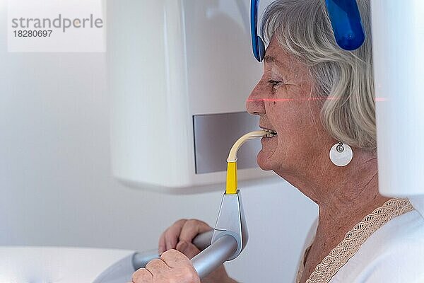 Zahnklinik  ältere Frau im Röntgenraum  die eine Röntgenaufnahme macht