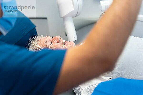 Zahnklinik  ältere Frau sitzt lächelnd beim Zahnarzt und wartet auf eine Zahnersatzuntersuchung