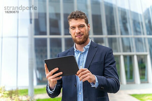 Porträt eines jungen männlichen Geschäftsmannes oder Unternehmers außerhalb des Büros  mit einem Tablet in der Hand