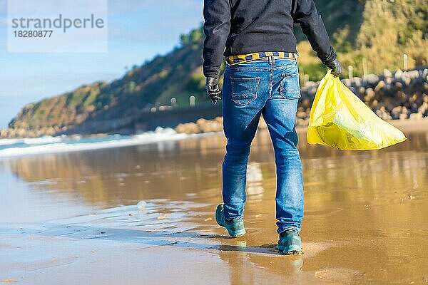 Meeresverschmutzung  nicht erkennbare Person  die am Strand spazieren geht und Plastik sammelt. ökologisches Konzept