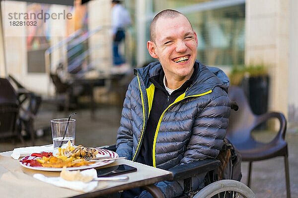 Porträt einer behinderten Person im Rollstuhl in einem Restaurant  die lächelt und Spaß hat