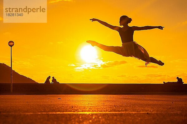 Silhouette einer jungen Tänzerin  die bei Sonnenuntergang einen Sprung am Strand vollführt und ein Tutu trägt