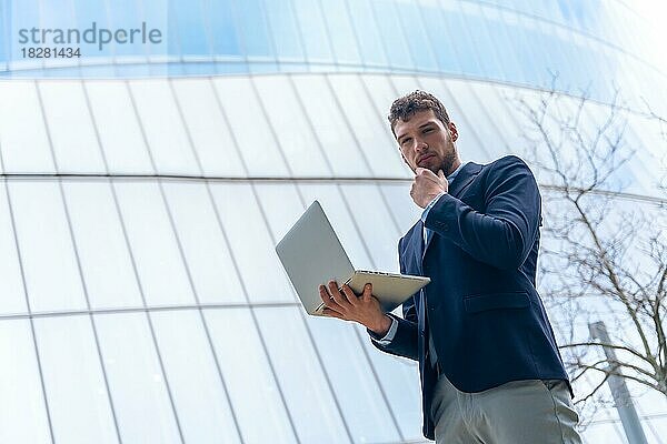 Junger Geschäftsmann mit einem Computer in einem Glasgebäude  Finanzkonzept