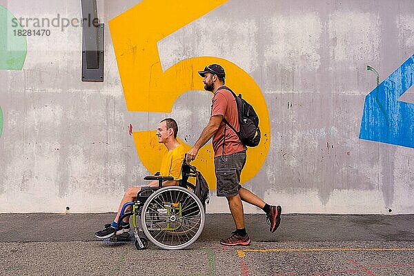 Behinderte Person im Rollstuhl an einer Betonmauer  im Gespräch mit einem Freund