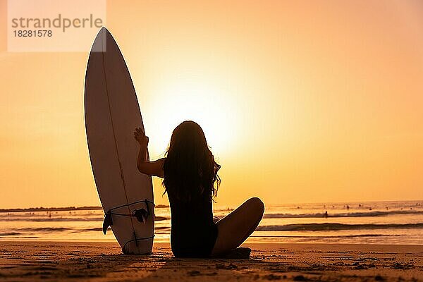 Silhouette Surferin am Strand bei Sonnenuntergang