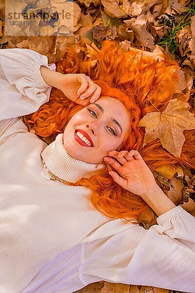 Rothaarige Frau auf Blättern in einem Waldpark liegend  Herbstzeit Lebensstil